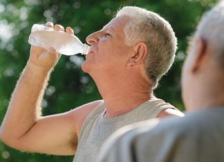 Image of seniors drinking water from a bottle in a park in summer to stop heat stroke