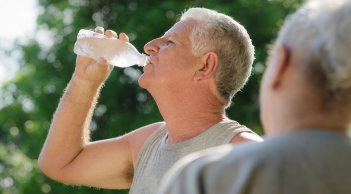 Image of seniors drinking water from a bottle in a park in summer to stop heat stroke