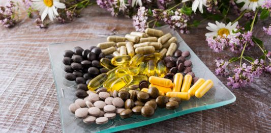 Image of a collection of menopause supplements on a glass dish surrounded by flowers