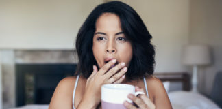 Banish winter tiredness Shot of a young woman yawning while having coffee in the morning at home