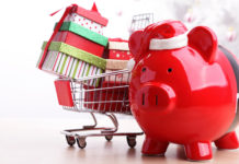 Saving money for Christmas Piggy bank with shopping cart in front of a white Christmas tree.