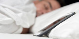 Orthosomnia - photo of a man asleep beside his phone.