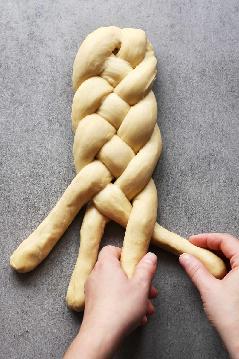 A pair of hands plaiting a bread loaf for happiness and wellbeing