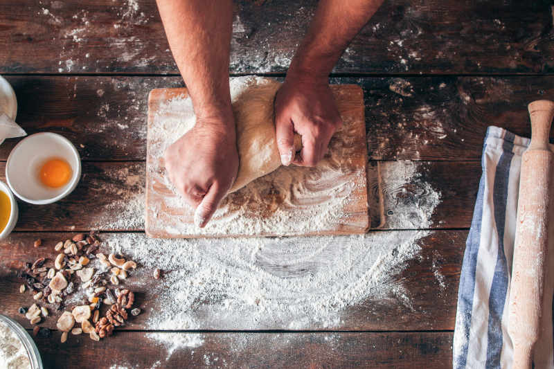 A pair of hands kneading dough on a floured surface ready for baking into bread
