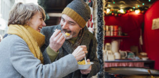 Christmas indigestion Mature couple are enjoying sharing some paella from a christmas market stall