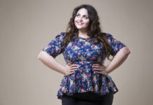Plus size fashion model in casual clothes, fat woman on beige studio background, overweight female body, professional make-up and hairstyle
