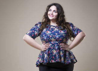 Plus size fashion model in casual clothes, fat woman on beige studio background, overweight female body, professional make-up and hairstyle