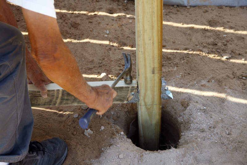 Dig a hole and erect the fence post using quick-drying cement.