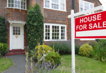 Sell your home fast For sale sign outside a house in an affluent suburb of London