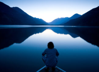 Spiritual places Person sitting quietly on the edge of a dock watching the sunset