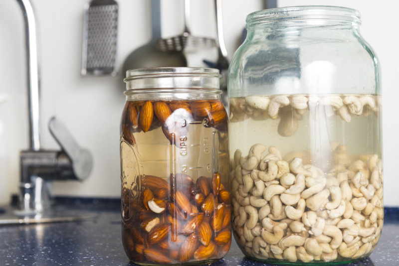 Activated nuts Soaked almonds and cashews in large glass in domestic kitchen.