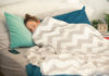 Young woman is sleeping in her cozy bed, covered with warm blanket.