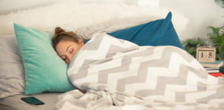 Young woman is sleeping in her cozy bed, covered with warm blanket.