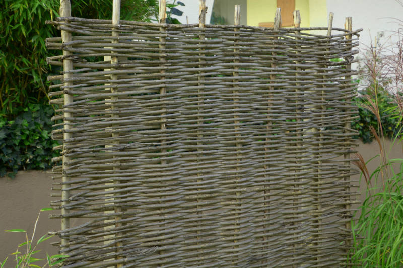 fence made of wicker decorates the property in the garden