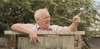Neighbour disputes Mature man shouting and pointing over a fence in the garden