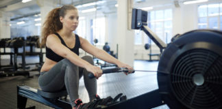 rowing machine benefits Girl in sportswear training on rowing-machine