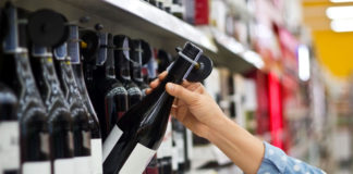 Woman is buying a bottle of wine at the supermarket background