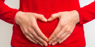 Signs of poor gut health hands showing sign of heart on red jumper