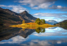 Amazingly still reflections of the island in Loch Leven, Scotland, with the Pap of Glencoe in the middle distance.