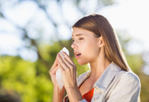 Woman using a tissue while sneezing in park (iStock/PA)