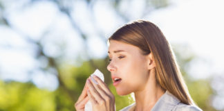 Woman using a tissue while sneezing in park (iStock/PA)