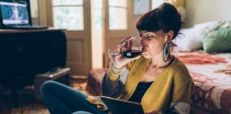 Stop drinking Young woman at home drinking red wine and using tablet