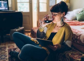 Stop drinking Young woman at home drinking red wine and using tablet