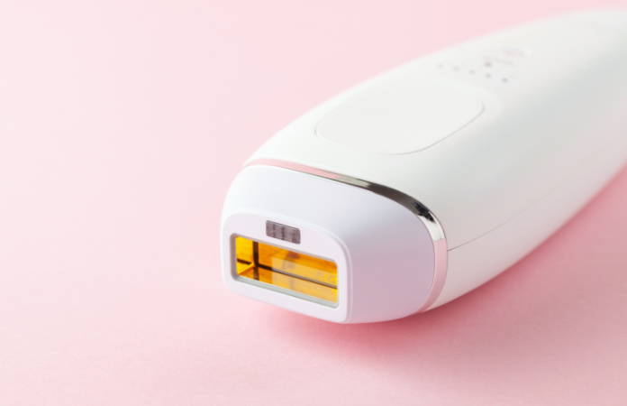Home spa accessories -  photoepilator on pink  background.