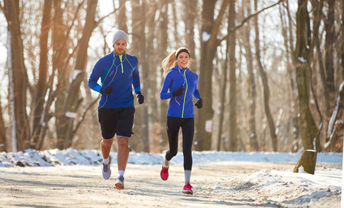 Young couple in the winter running together in nature