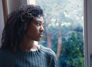 Dealing with seasonal Affective Disorder - young worried woman looking out of the window