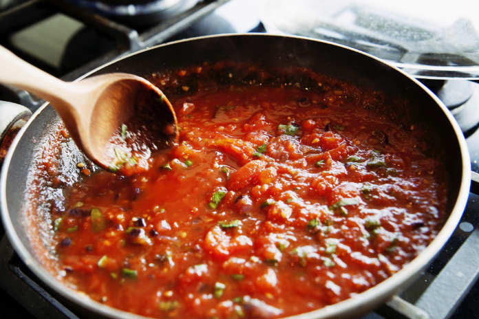 preparing of a homemade tomato sauce in a frying pan from fresh tomatoes.
