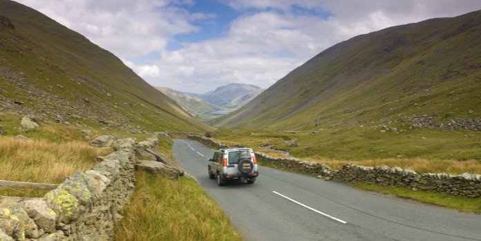 "Silver 4x4 sports utility vehicle crossing the dramatic Kirkstone Pass from Windemere to Ullswater in the beautiful English Lake District, Cumbria, UK.