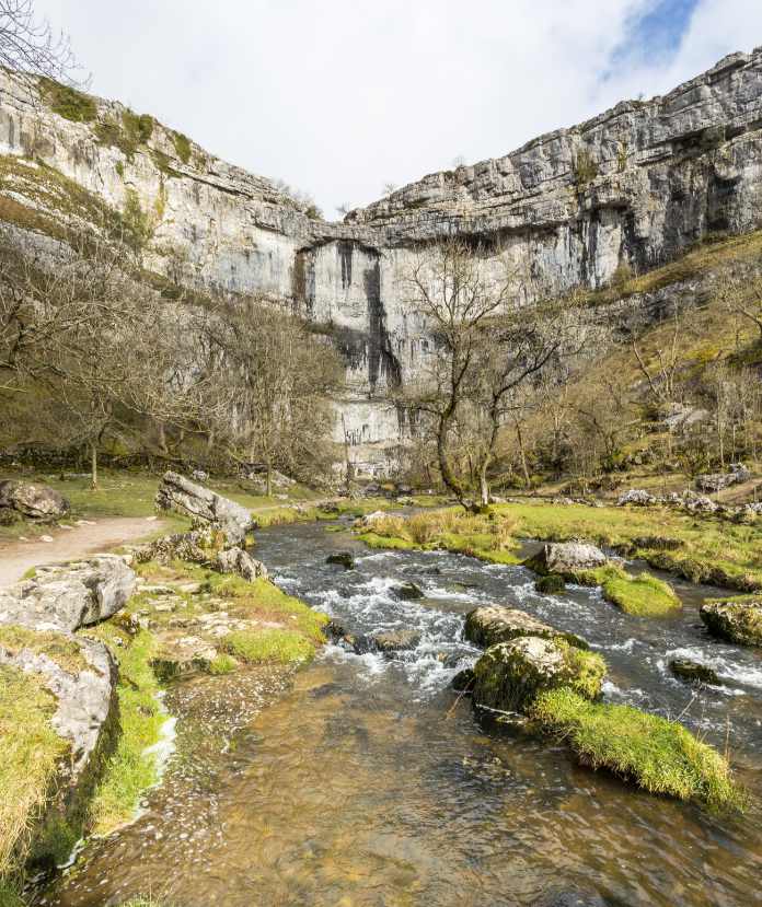 A view at Malham Cove, a huge curved limestone cliff, near Malham, Yorkshire Dales, Northern England.