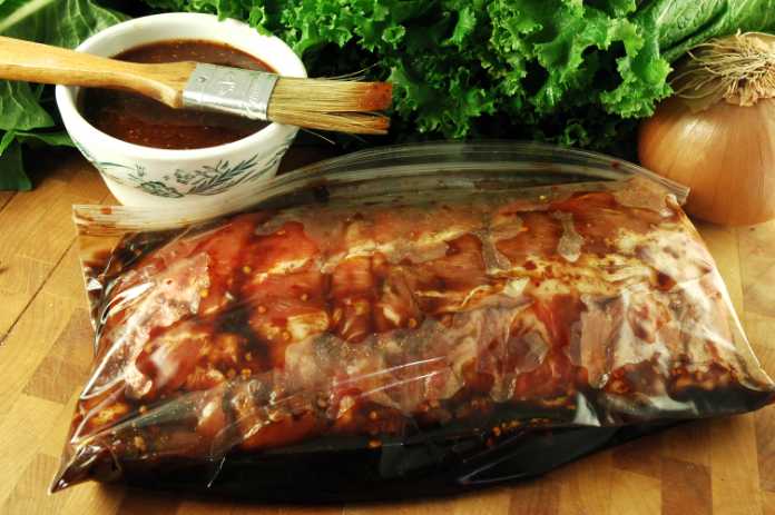 Fresh pork baby back ribs marinating in a plastic bag on a kitchen cutting board