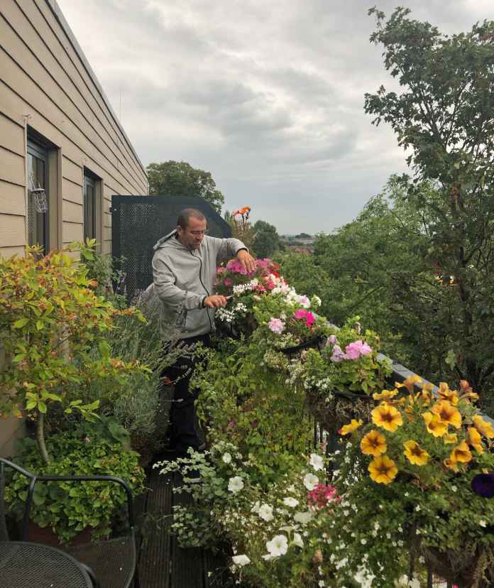Garden Organic's Chris Collins looks after the hanging plants on his balcony (Garden Organic/PA)