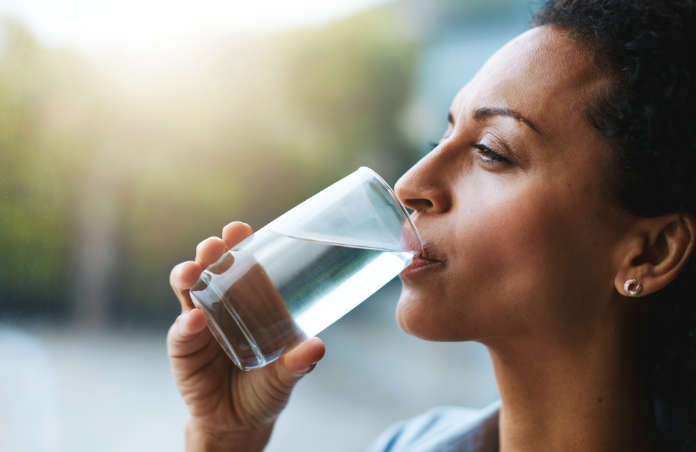 Shot of a woman drinking a glass of water at home