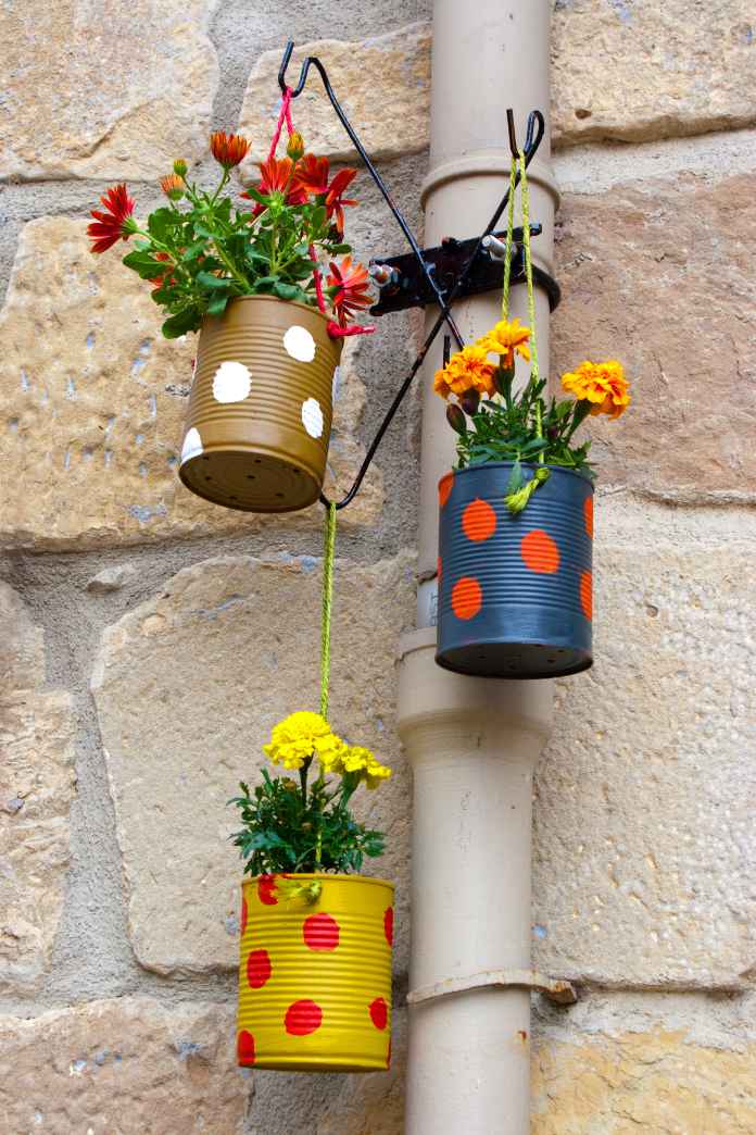 Hanging flowerpots made with cans in the street.
