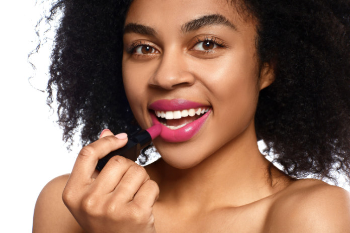 A women putting pink lipstick on 