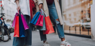 Two people holding colourful shopping bags, participating in sustainable shopping