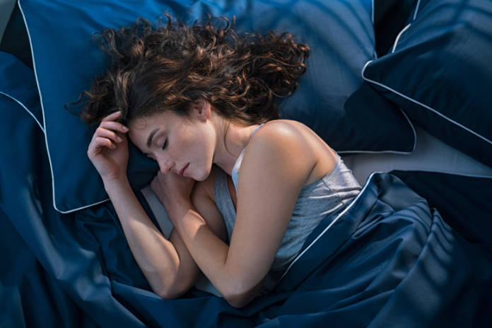 Top view of young woman sleeping on side in her bed at night. 