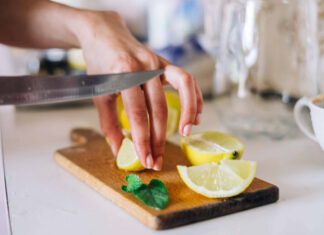 Someone cleaning a chopping board with lemon