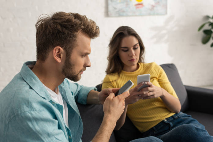 Selective focus of addicted couple using smartphones on couch