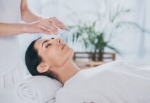 Woman with closed eyes receiving reiki treatment above head