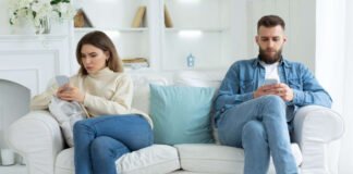 Digital detox Couple at opposite ends of sofa on their phones
