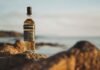 Scotch whisky A bottle of Torabhaig positioned on some rocks by the sea