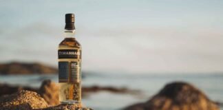 Scotch whisky A bottle of Torabhaig positioned on some rocks by the sea