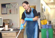 A hospital cleaner mops the floor in a ward in a modern UK hospital