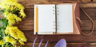 Plant calendar A notebook with garden tools, gloves and flowers on a table