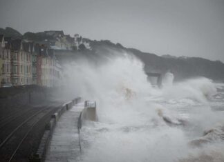 Storm Callum causes huge waves to crash across trains as they travel along the seafront at Dawlish, Devon, UK.
