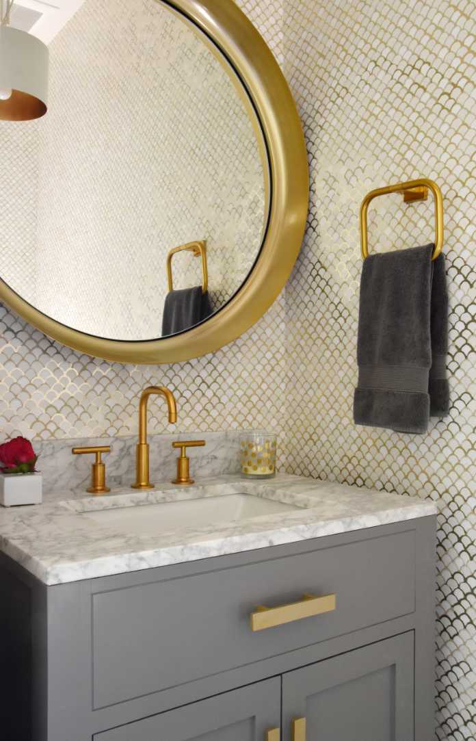 A metallic gold wallpaper effect paired with brass taps, gold fittings and an oversized mirror adds instant glamour